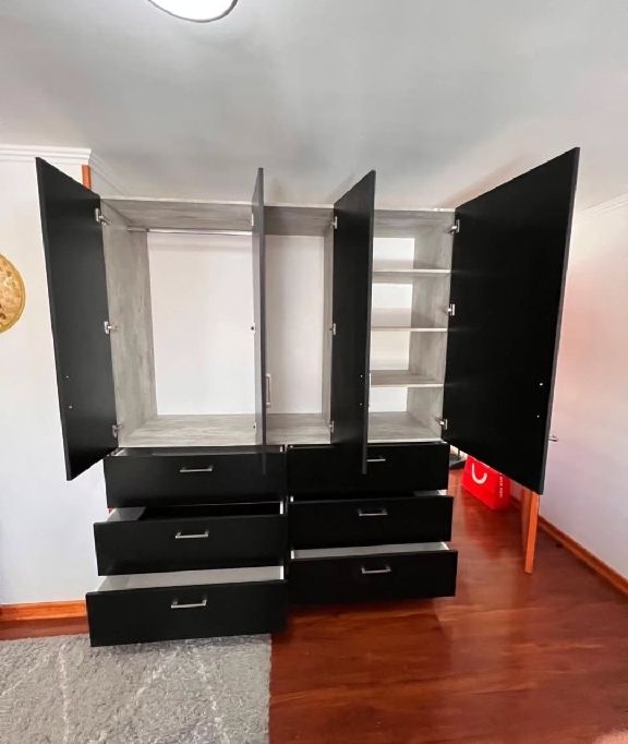 Armario lacado en negro con puertas abiertas, interior gris y cajones inferiores