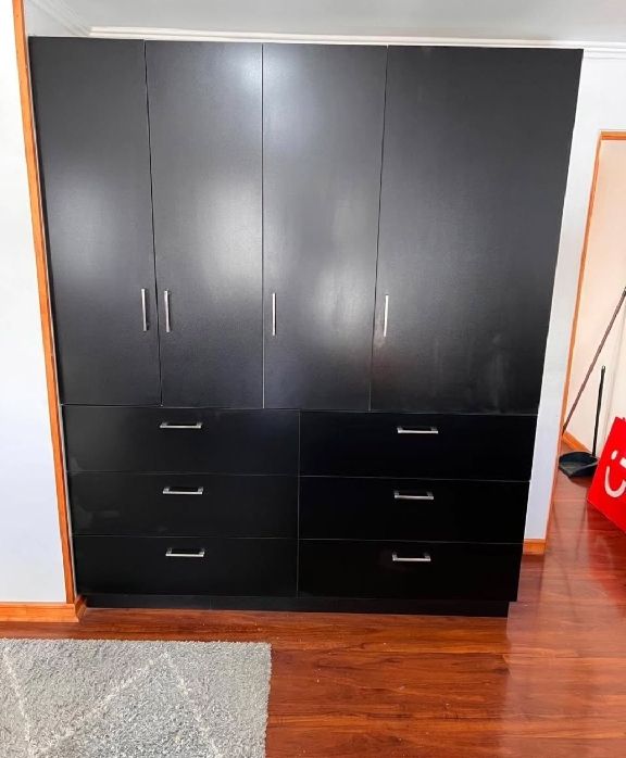 Armario lacado en negro con seis cajones y puertas altas con tiradores metálicos
