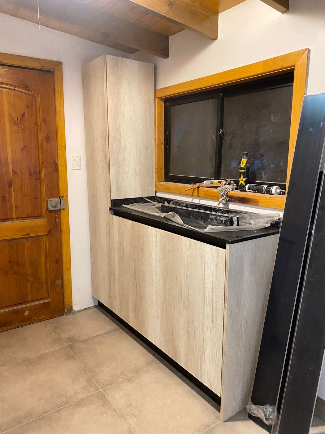 Mueble de cocina en obra con puertas lacadas en blanco junto a ventana de madera