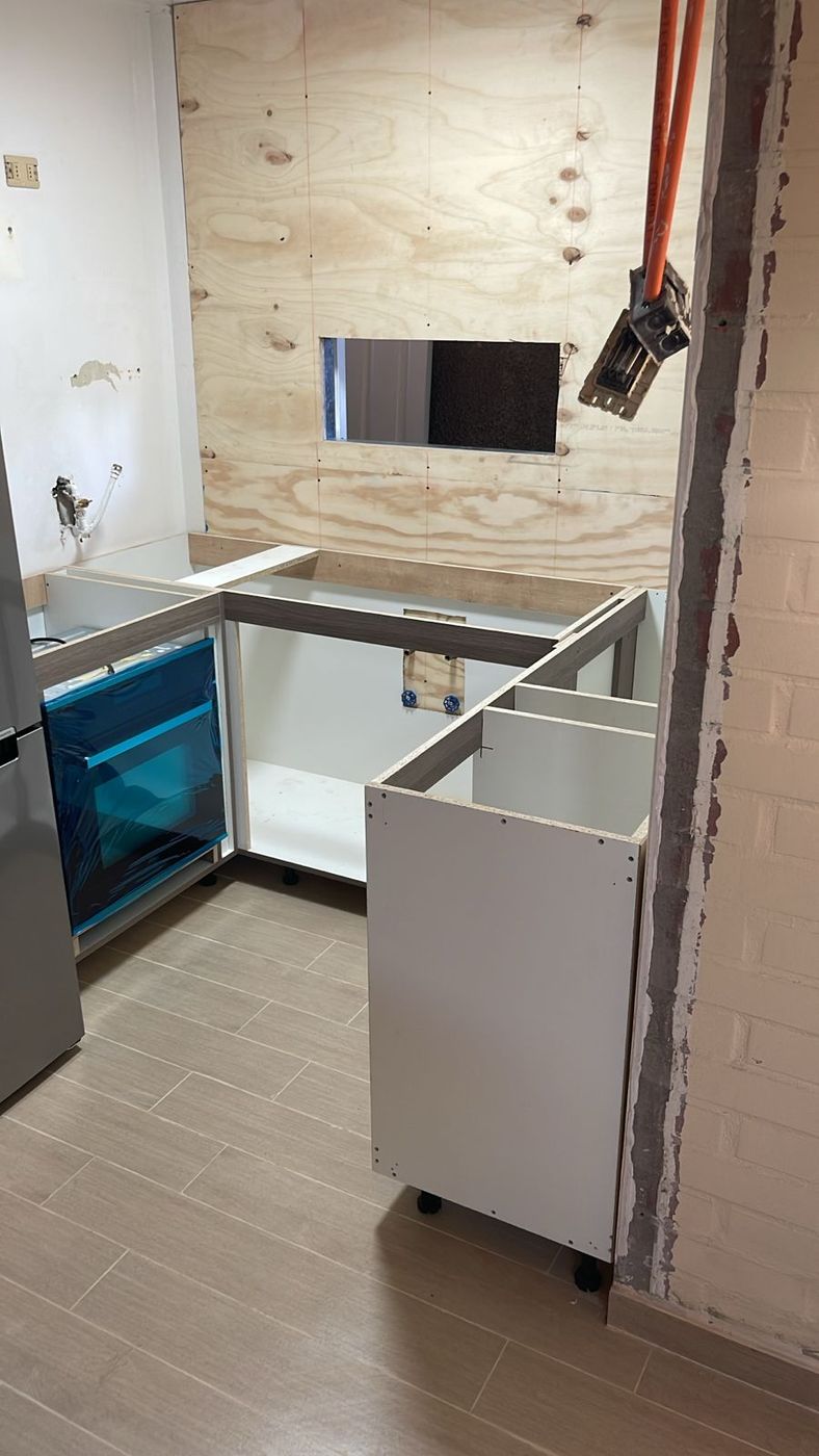 Estructura de muebles de cocina en montaje, con panel de contrachapado y tubos de gas