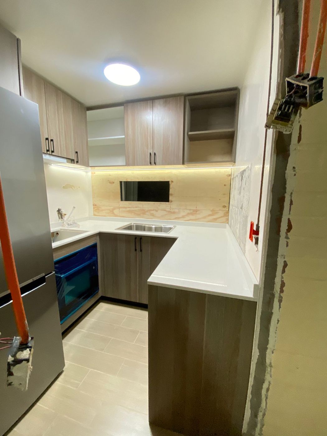 Cocina pequeña en U casi terminada en Ferrol, con encimera blanca y frigorífico integrado