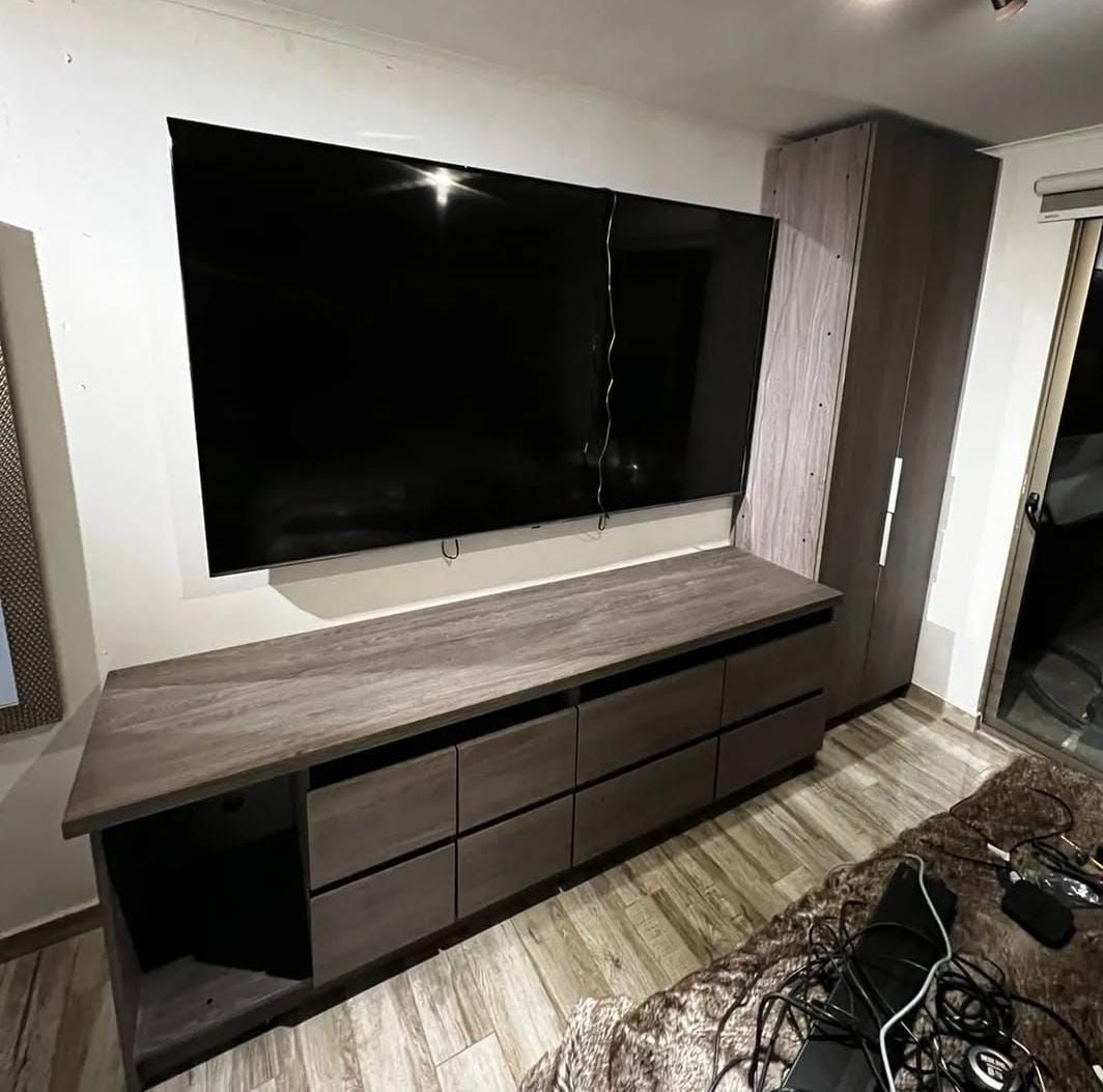 Mueble bajo de televisión en madera grisácea con cajones y armario columna a juego
