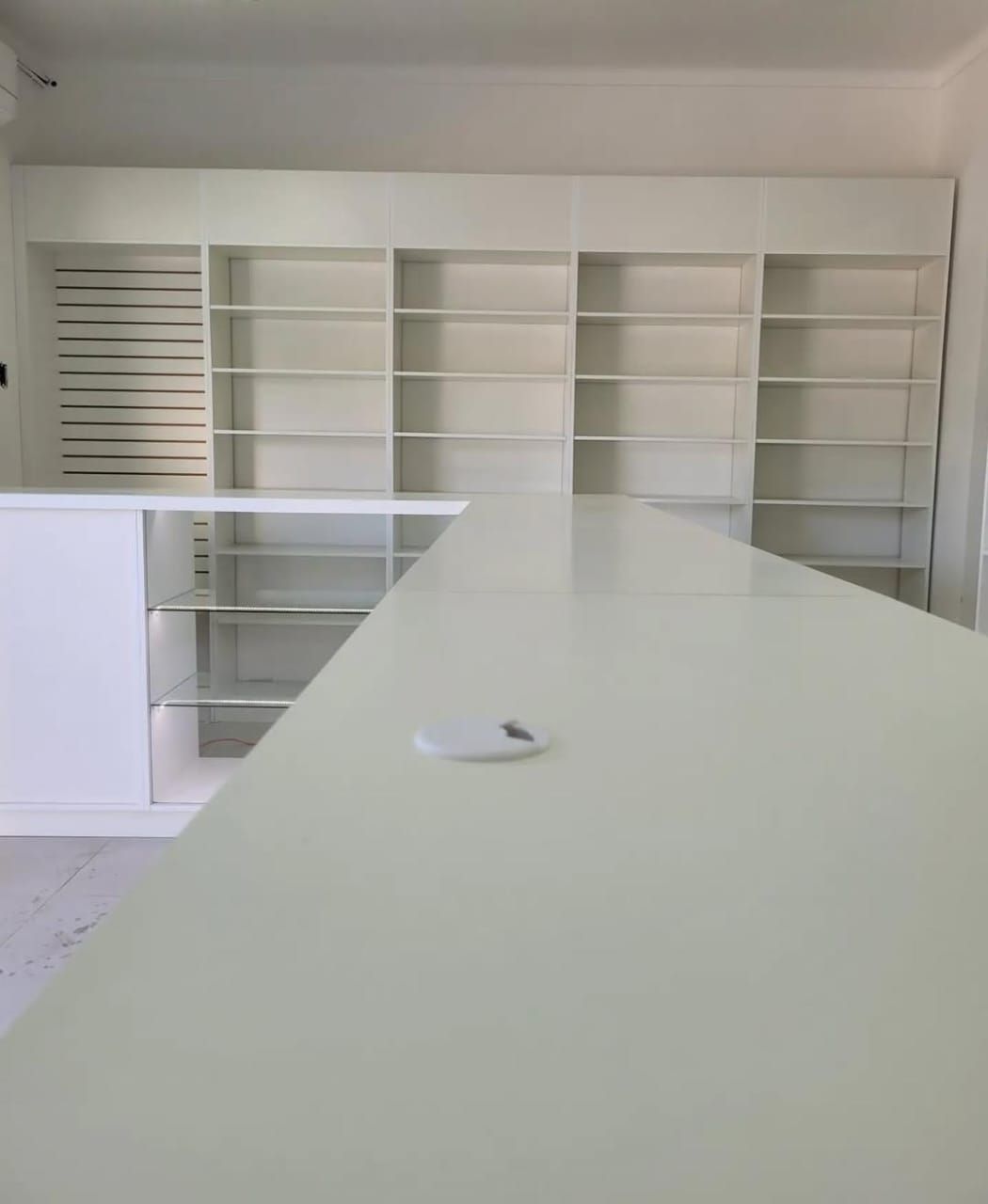 Estanterías blancas a medida en local comercial con mostrador en L