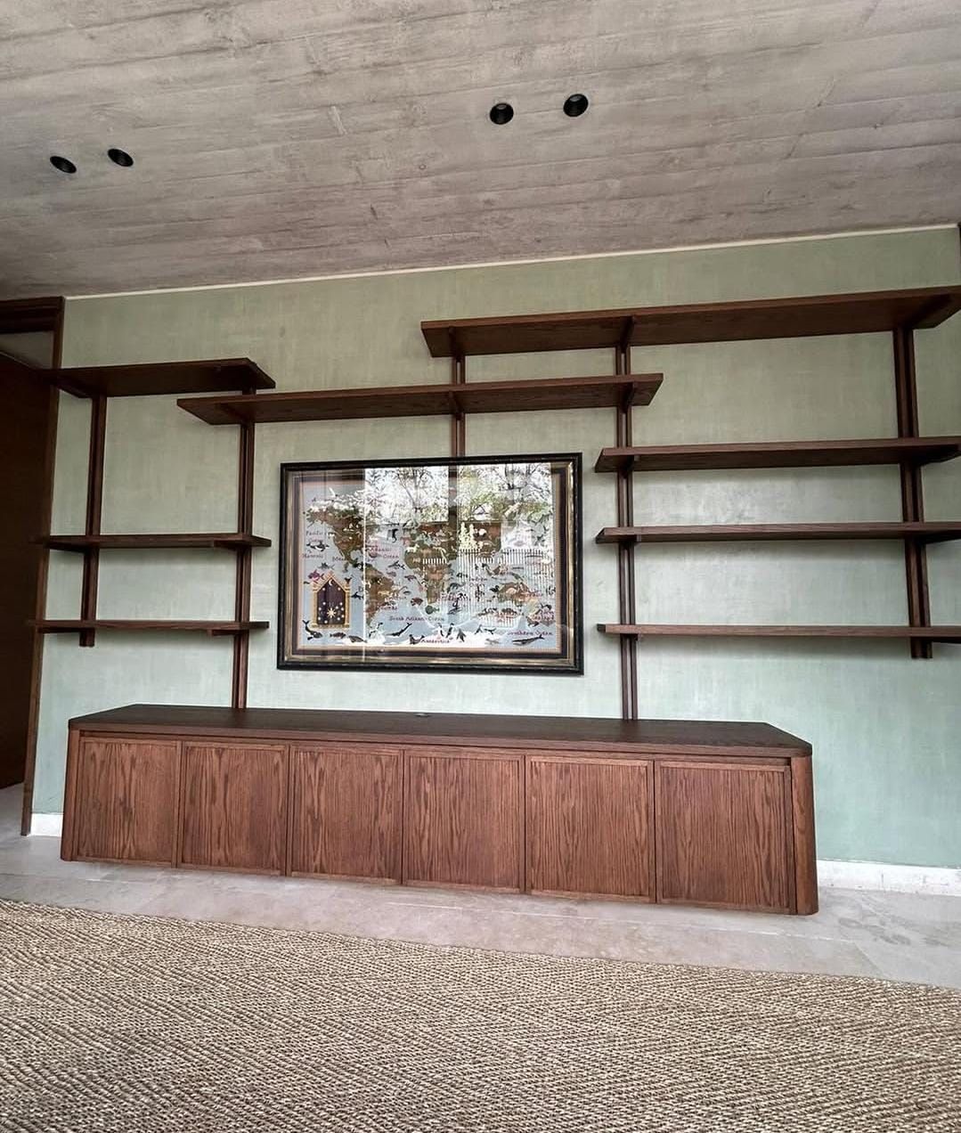 Librería abierta de estructura oscura con mueble bajo, sobre alfombra de fibra natural