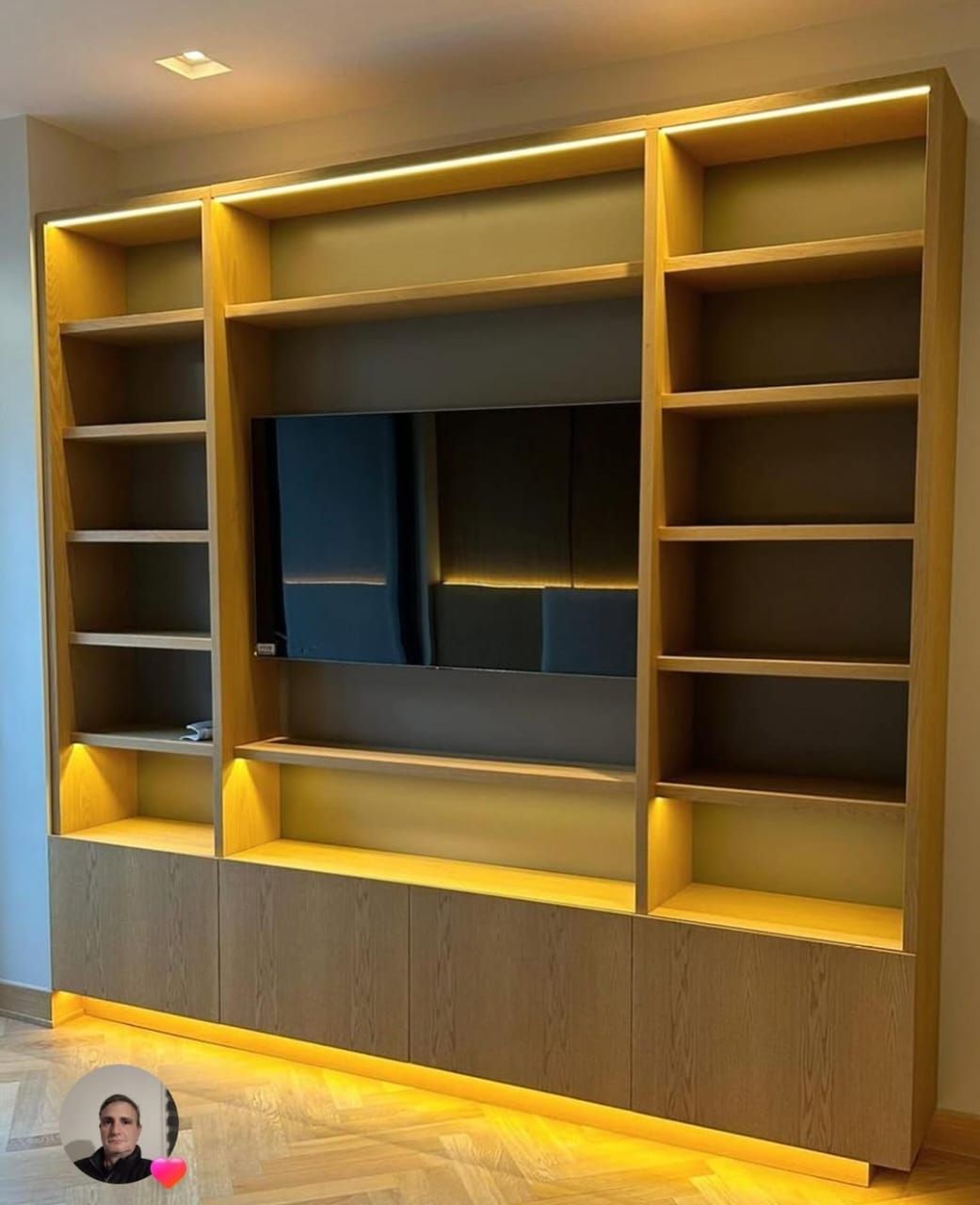 Vista frontal de librería en un salón de Ferrol, con televisor empotrado y baldas iluminadas