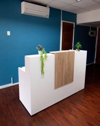 Mostrador de recepción escalonado en un local de Ferrol, en blanco con panel de madera