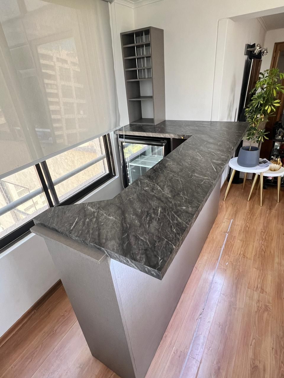 Barra de bar con encimera de mármol gris oscuro veteado y mueble expositor