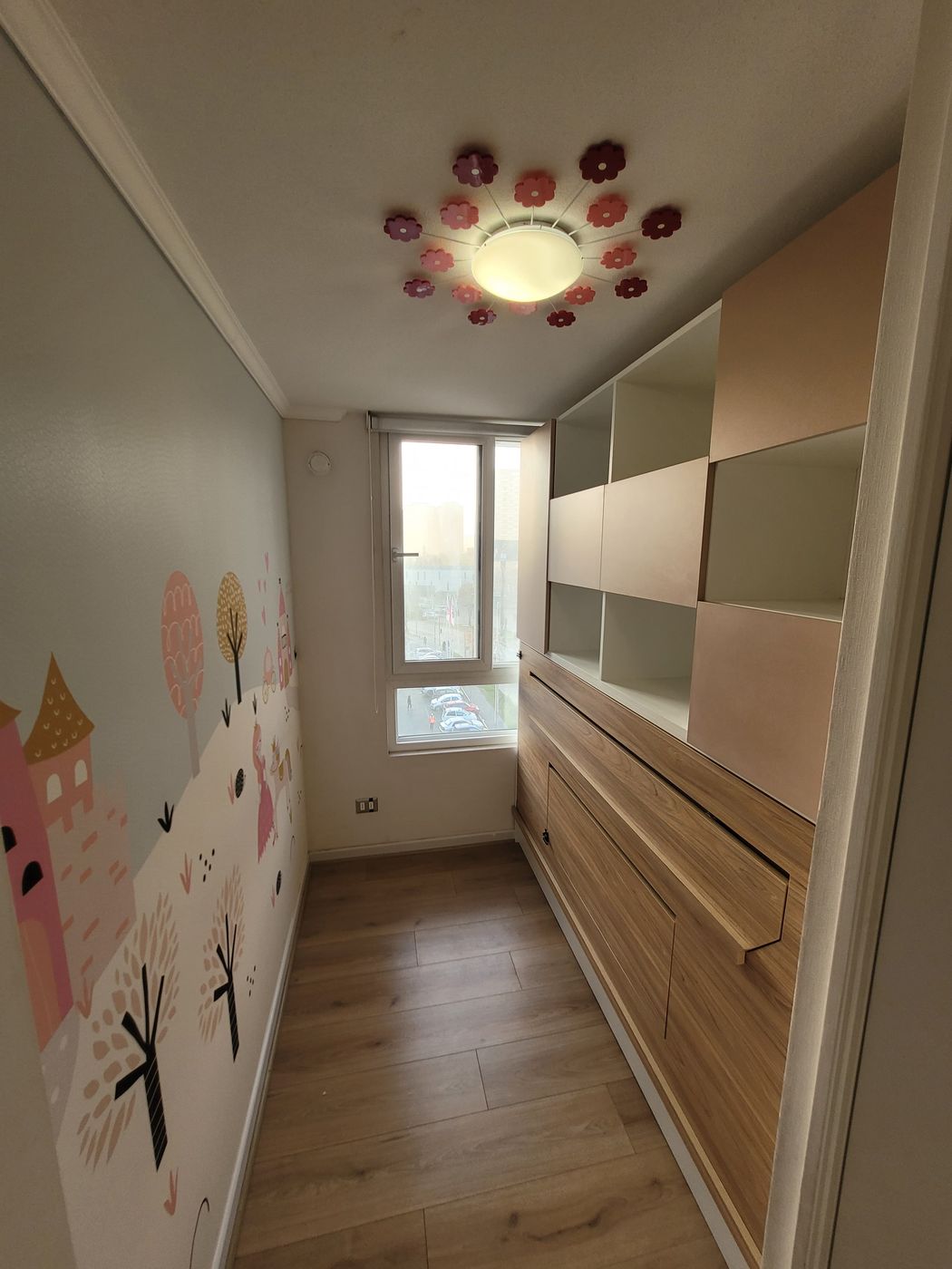 Detalle de mueble infantil con estantería en rosa y beige sobre cajonera de madera