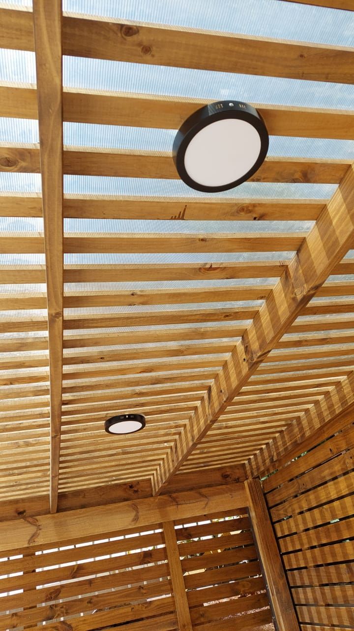 Detalle de estructura de pérgola de madera con foco circular negro