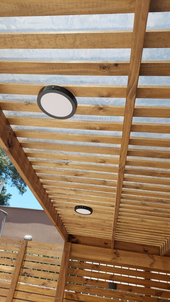 Pérgola de madera con doble foco empotrado y celosía lateral de lamas