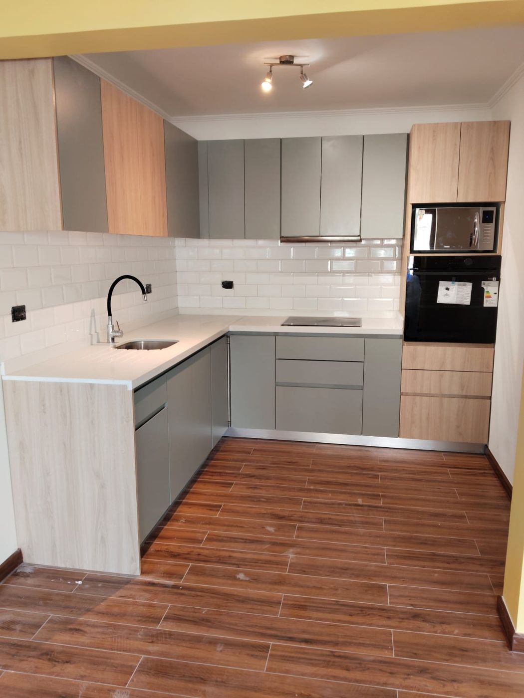 Detalle de placa de inducción y horno con microondas empotrados en cocina de Ferrol