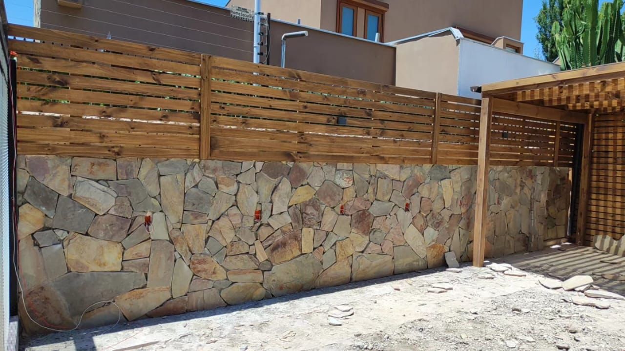 Patio con muro de piedra y pérgola, obra terminada