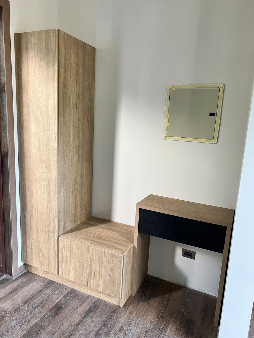 Rincón de dormitorio en Ferrol, con armario alto en madera clara y tocador lacado en negro