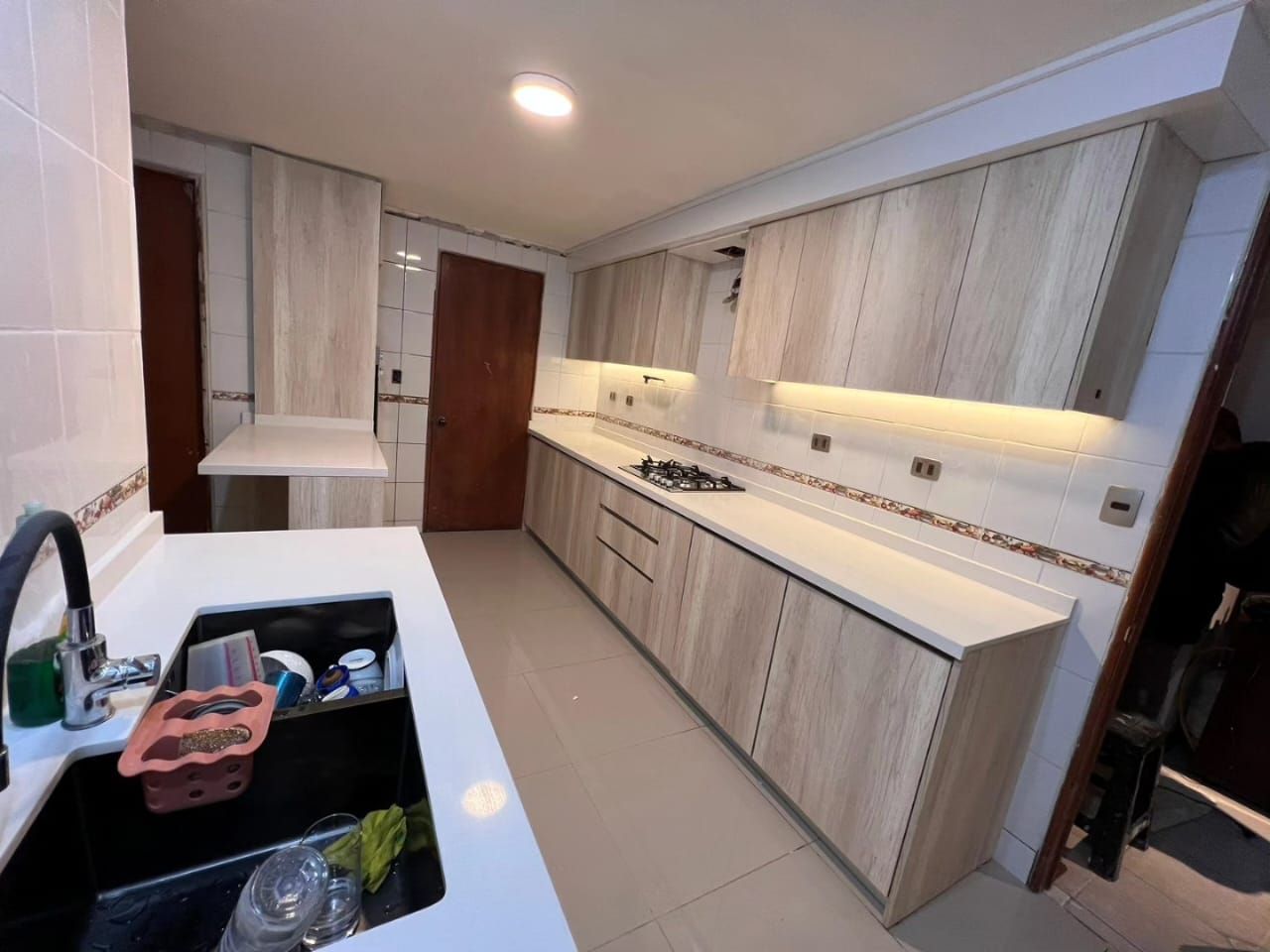 Cocina alargada en una casa de Ferrol, en madera clara con placa de gas y fregadero