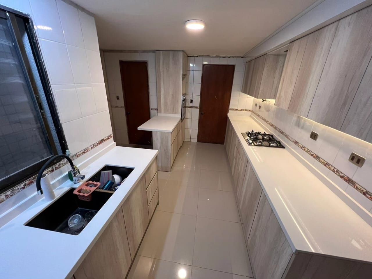 Cocina de paso con puertas de madera antigua, placa de gas y suelo de gres brillante