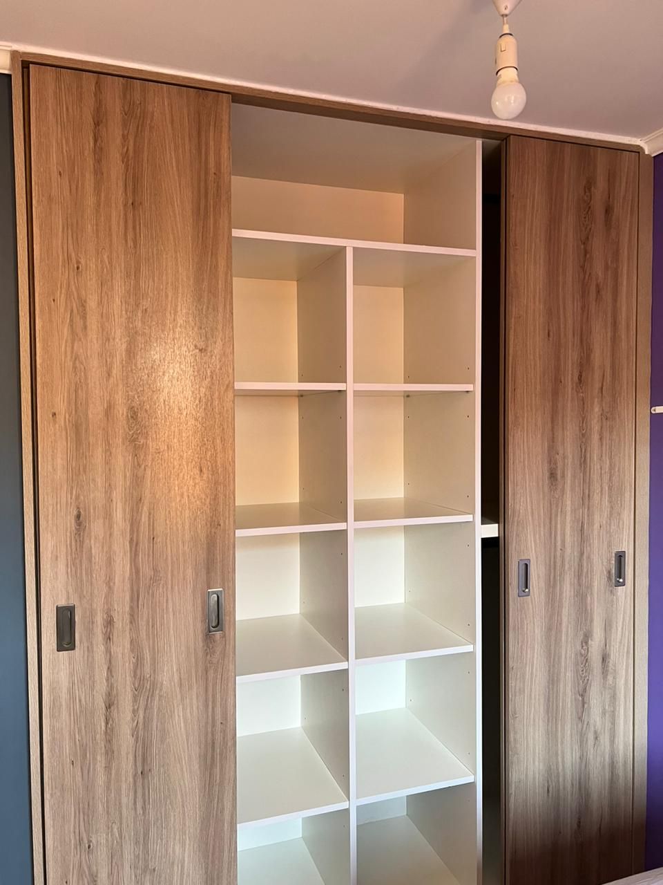 Detalle de armario correlero en madera con interior de estanterías cubo iluminadas